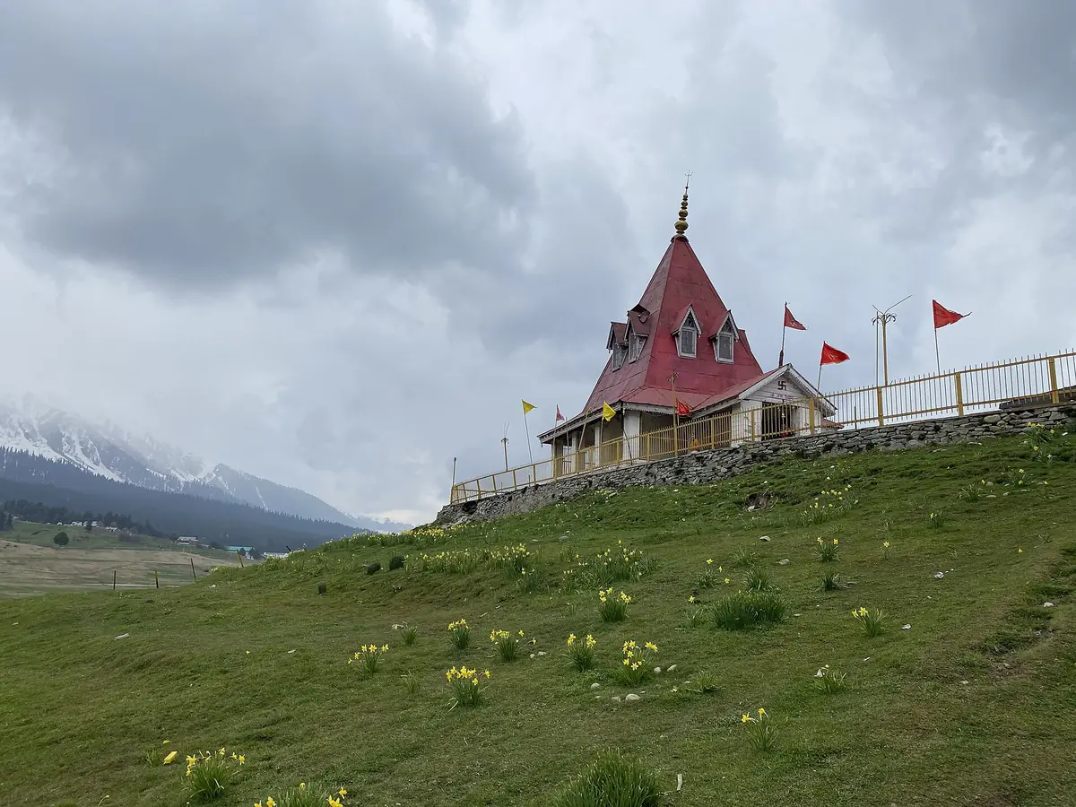 The red-roofed Maharani Temple on a green hillock in Gulmarg